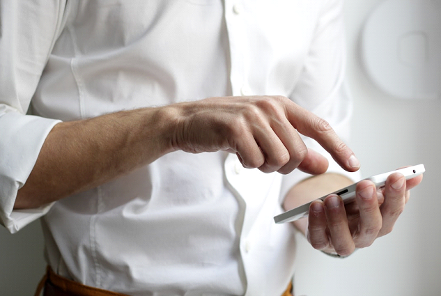 A man using texting software for nonprofits on his smartphone to enhance outreach efforts.